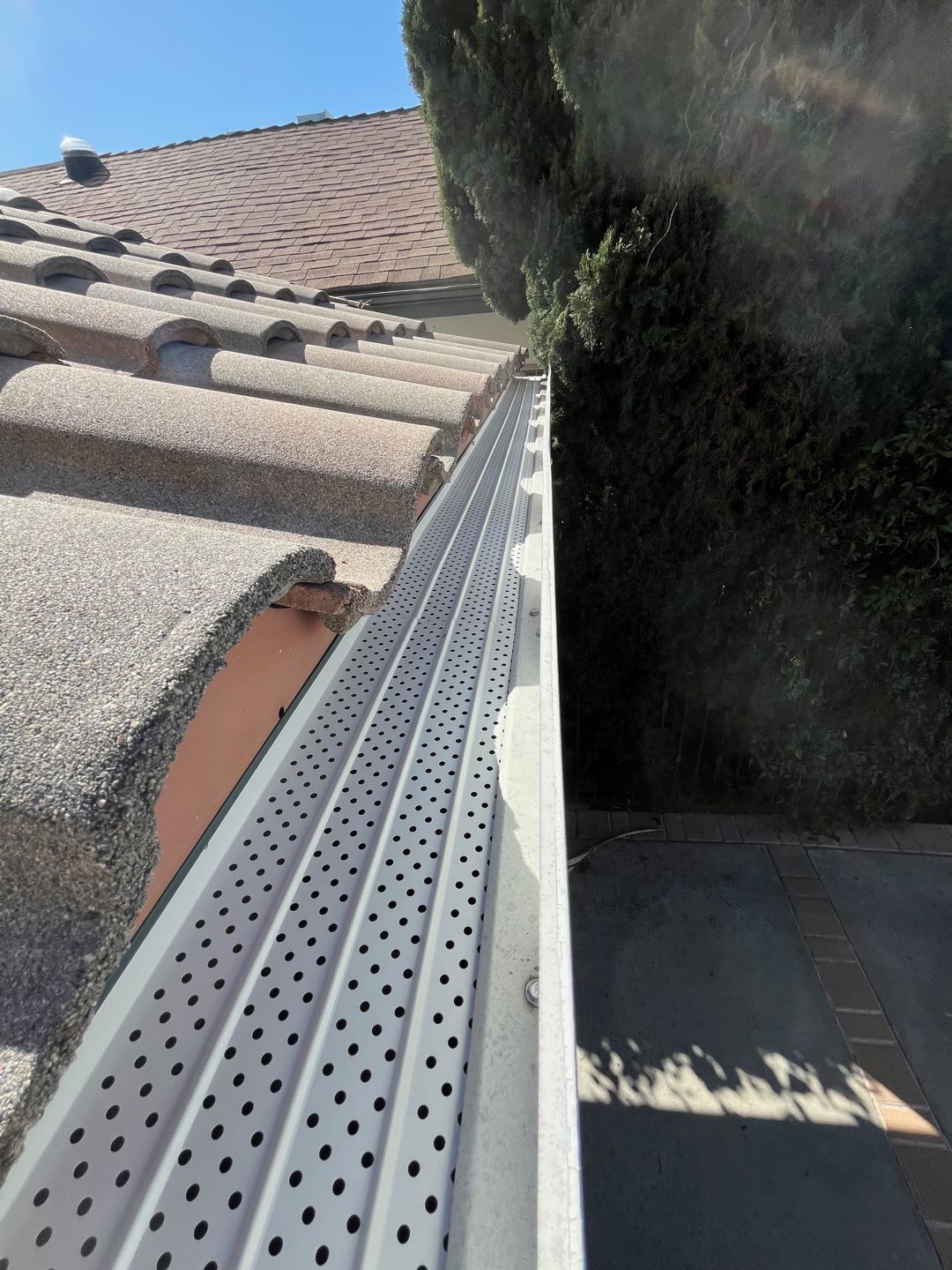 Perforated gutter guard over a gutter along a tile roof in the Los Angeles area