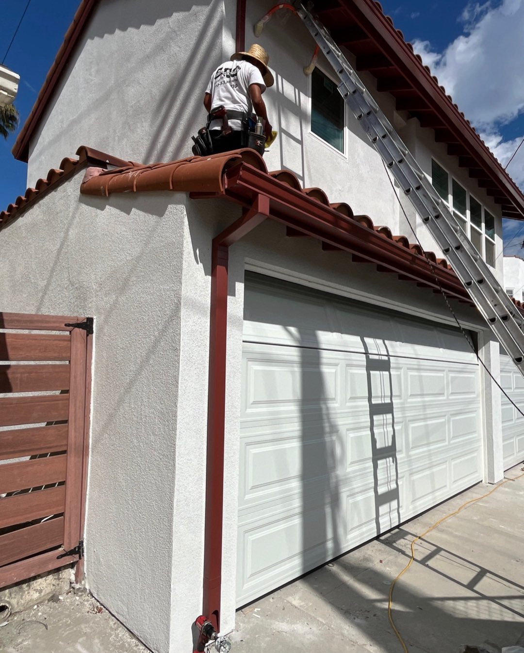 Red K-style gutter and downspout on a stucco home with a Spanish tile roof in the Los Angeles area