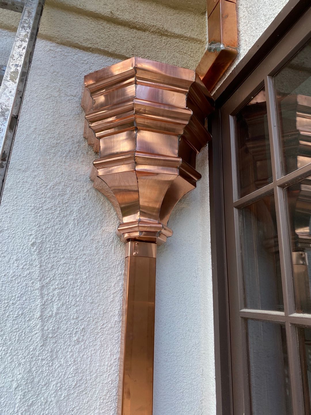 Custom copper leader head and downspout on a stucco wall in the Los Angeles area