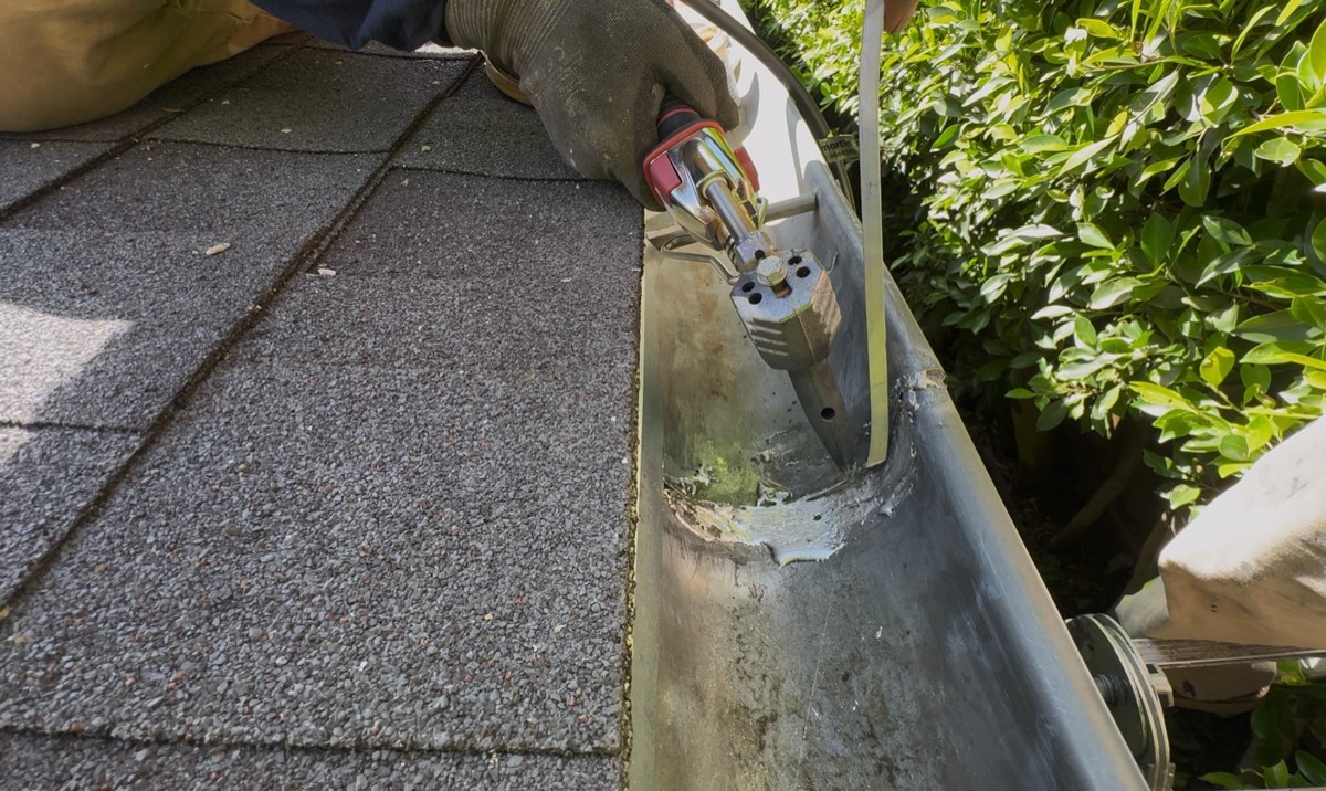 Gutter repair in the Los Angeles area: resealing a seam inside an aluminum gutter at the roof edge